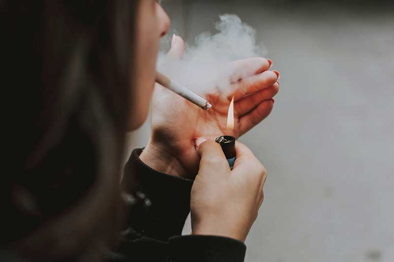 Bilde av dame som tenner en sigarett. Foto: lilartsy, Unsplash